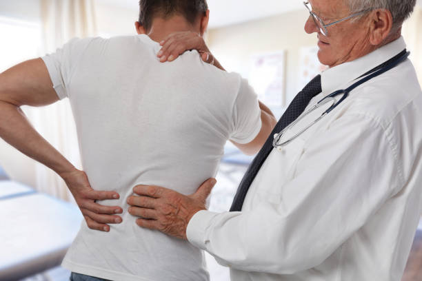 hombre doctor y paciente que sufre de dolor de espalda durante el examen médico. - shoulder pain backache men fotografías e imágenes de stock