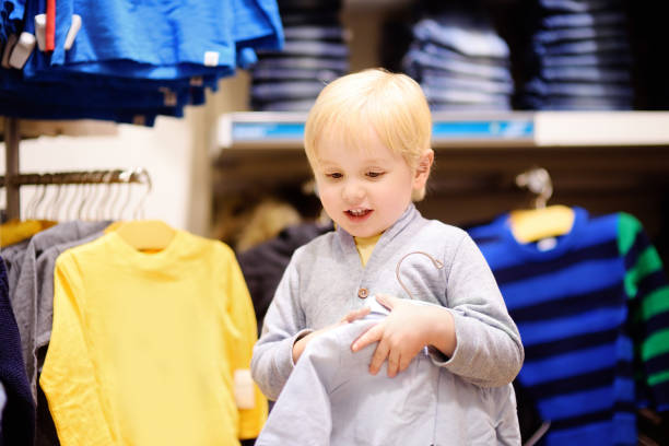 menino bonitinho tentando novas roupas durante as compras - 5563 - fotografias e filmes do acervo