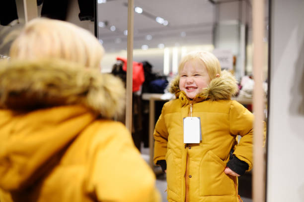 симпатичный маленький мальчик пытается новое пальто во время покупок - 5560 стоковые фото и изображения