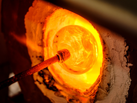 A glass blowing furnace being used to heat a piece of glass for blowing.