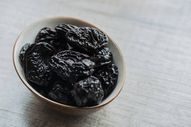 istock prunes in brown plate on a white background. Close-up 863162154