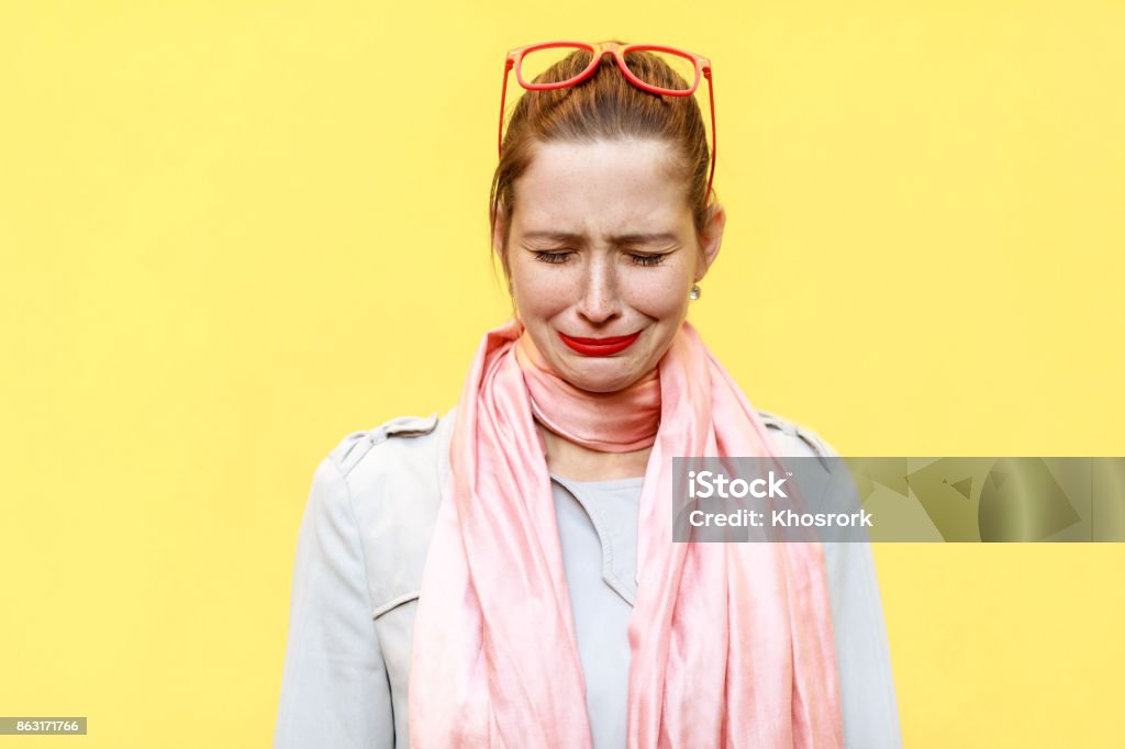 Portrait of unhappy and depressed young caucasian woman with ginger hair feeling ashamed or sick. Human face expressions and emotions concept. Portrait of unhappy and depressed young caucasian woman with ginger hair feeling ashamed or sick. Human face expressions and emotions concept. Isolated studio shot yellow background. Colored Background Stock Photo