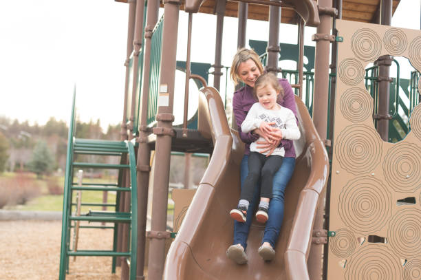 istock Mom and daughter ride down a slide together 863177574