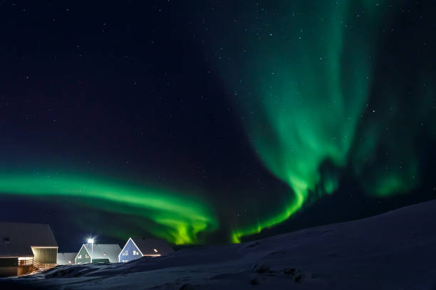 Photo of Arctic village and green waves of Northern lights in a suburb of Nuuk, Greenland