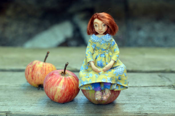 istock Dollhouse Doll Sitting on a Real Apple 863190668