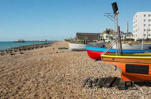 Fishing boats drawn up on shingle beach at the seafront in Worthing, West Sussex, England