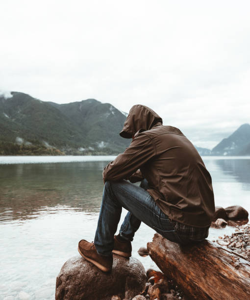 solitude man sitting on the river in british columbia solitude man in canada spirituality adventure searching tranquil scene stock pictures, royalty-free photos & images