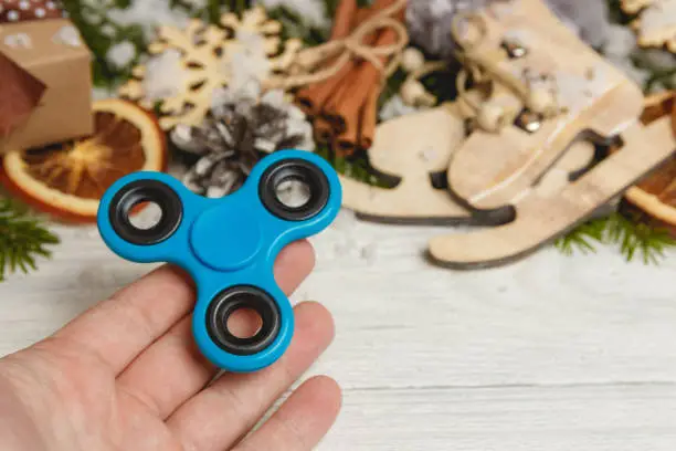 Photo of Hand with Spinner on white wooden table with christmas decoration