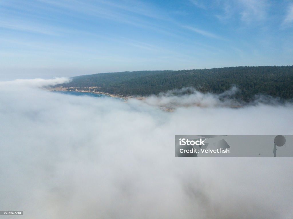 Aerial View of California Marine Layer of Fog Fog drifts across the beautiful northern California coastline in Sonoma. Thick fog, generated by a layer of cool, coastal air trapped beneath a layer or warm, dry air, is common in this scenic region. Adventure Stock Photo