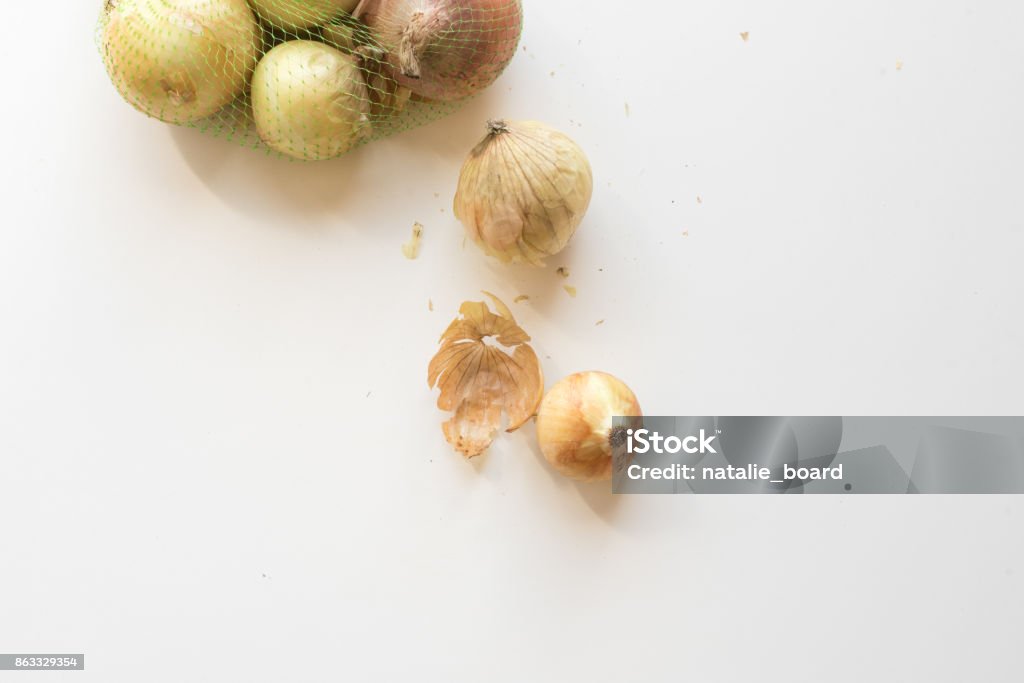 Onions on white table from above High angle view of natural looking brown onions on white table and in bag (selective focus) Above Stock Photo