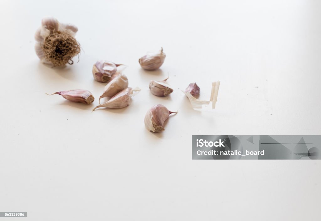 Unpeeled garlic cloves Unpeeled garlic cloves on white table (selective focus) Australia Stock Photo