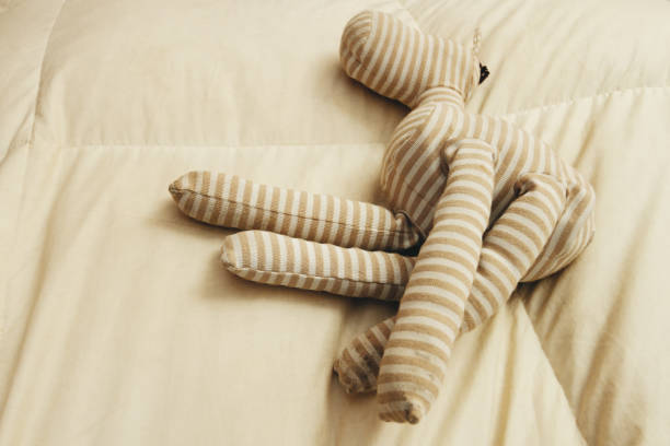 istock Cloth rag doll on white blanket of a bed with sunlight seen from above 863331852