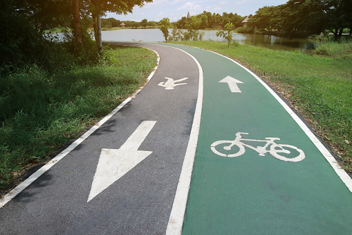 Bicycle path drawn on the green asphalt road. Lanes for cyclists and run. The route for exercise.