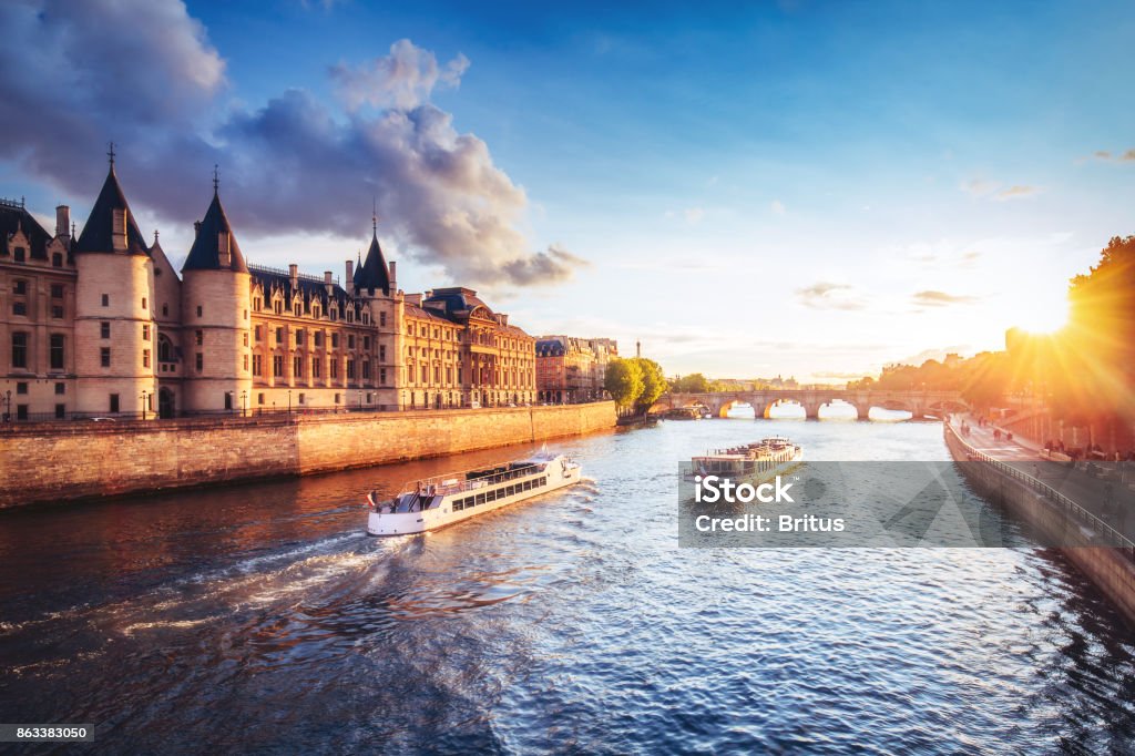 Dramatic sunset over river Seine in Paris, France, with Conciergerie and cruise boats. Dramatic sunset over river Seine in Paris, France, with Conciergerie and Pont Neuf. Colourful travel background. Romantic cityscape. Cruise - Vacation Stock Photo