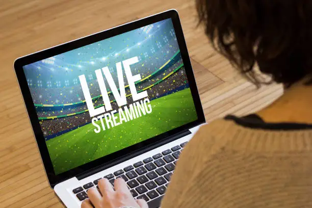 live streaming concept: live streaming text on a stadium on a laptop screen. Screen graphics are made up.