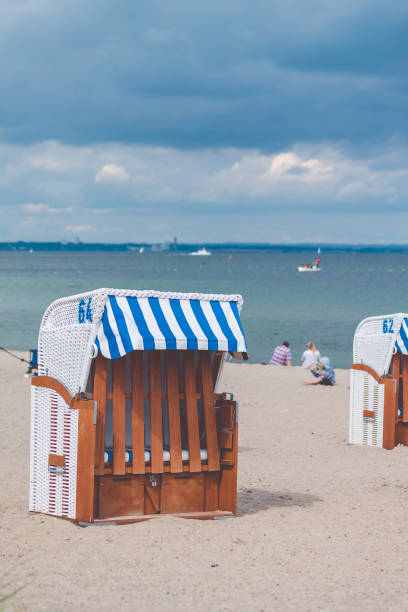 Blue striped roofed chairs on empty sandy beach in Travemunde. Blurred people in background