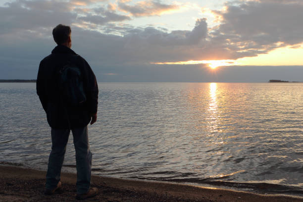 istock Man standing on the riverbank at sunset 863436608