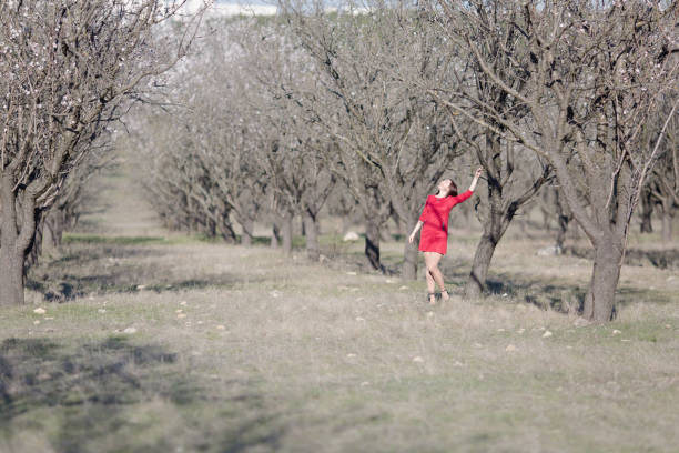 Little girl holding up an apple with a basket of fruit in hand.