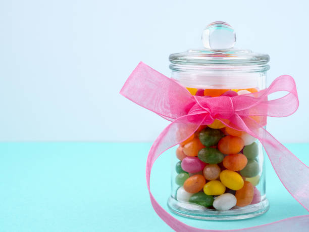istock glass jar with sweets, candy, with a bow of pink ribbon on a turquoise table. Sweets with empty space for text 863450762