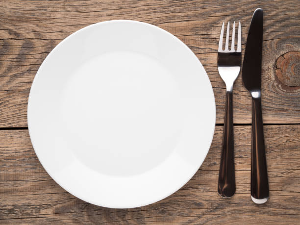 istock Blank flat plate, knife, fork on a wooden rustic table, top view. 863451054