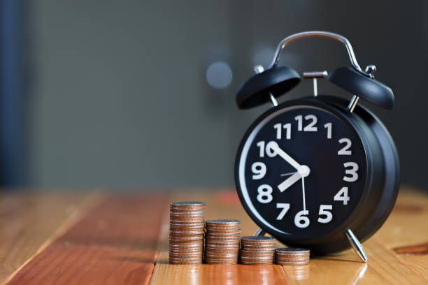 istock Alarm clock and step of coins stacks on working table, time for savings money concept. 863459404