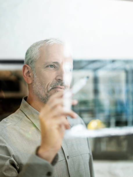 istock Confident mature businessman writing on glass wall 863477128