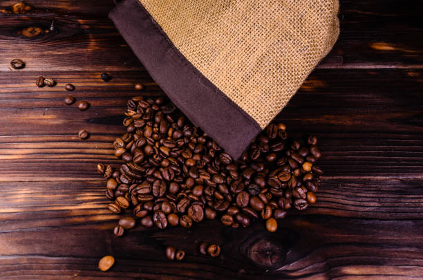 istock Roasted coffee beans in sack on wooden table. Top view 863482598