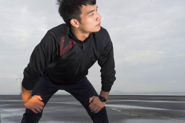 young asian athlete resting with sweat pouring after exercising