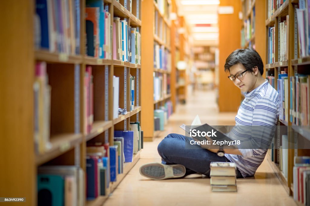 Jeune homme asiatique Université étudiant lecture de livre dans la bibliothèque - Photo de Peuples d'Asie et du sous-continent indien libre de droits