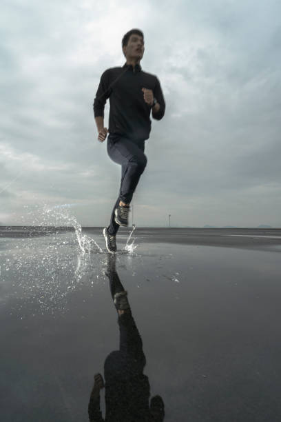 istock running in splashing water against cloudy sky 863493042