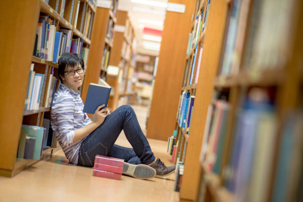 istock Young Asian man university student reading book in library 863497594