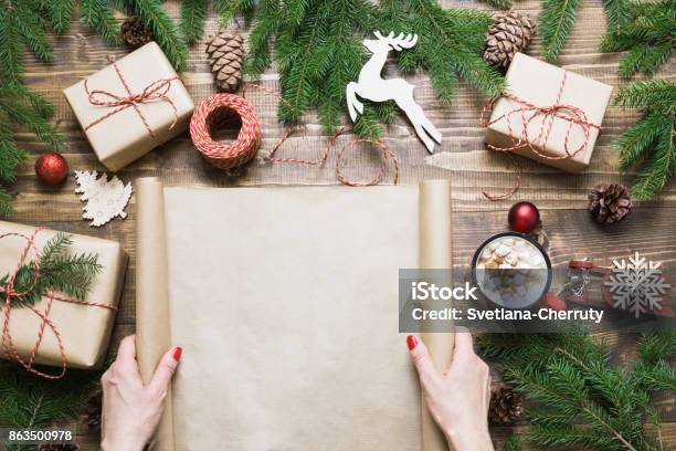 Christmas Composition Female Holding Empty Scroll Wishlist For Santa Claus Or Holiday Cheers Laid On A Wooden Table With Christmas Giftbox And Decor Flat Lay Top View Copy Space Stock Photo - Download Image Now