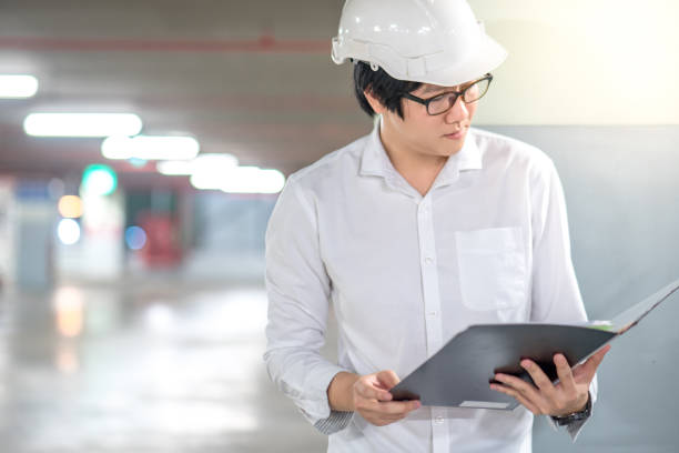 istock Young Asian Engineer or Architect holding files while wearing personal protective equipment safety helmet at construction site 863501872