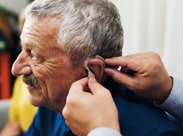istock Doctor inserting hearing aid to patient's ear 863504880