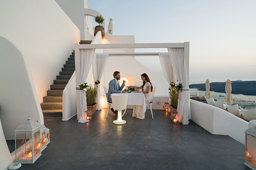couple having candlelight dinner on romantic terrace with seaview honeymoon, vacation