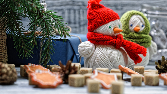 Rustic white wood table with Christmas cookies and sugar cubes decorated with xmas tree twigs and blue gift box. Handmade snowmen on the table. Close-up