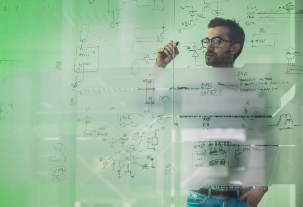 istock Young male engineer drawing a diagram on a glass wall. 863509080