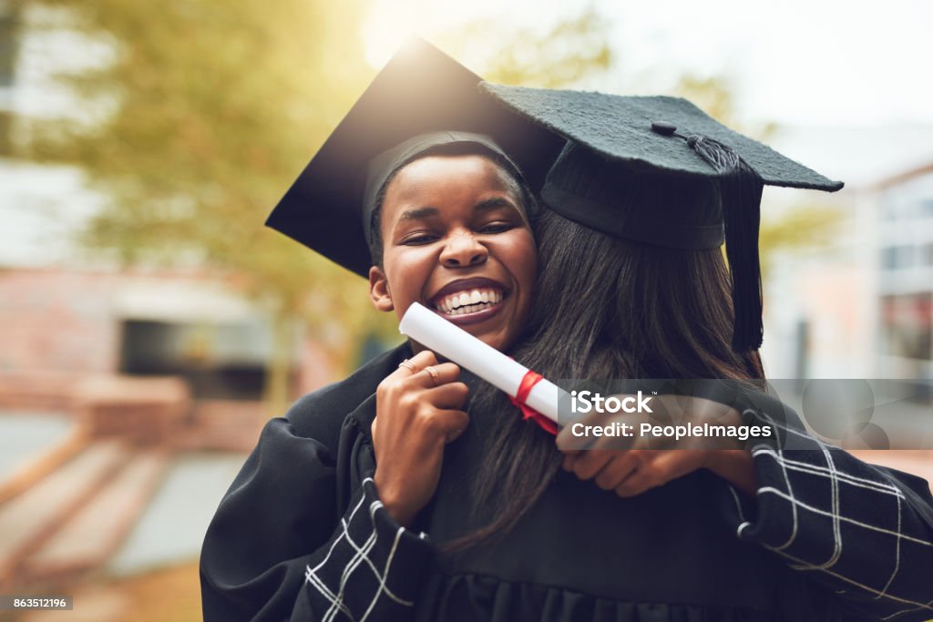 Our friendship got us through a lot of long nights Shot of two graduates embracing each other on graduation day Graduation Stock Photo