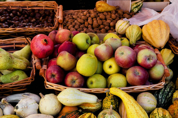 many basket of apples, pears, chestnuts, walnuts, pumpkins, fruit and vegetables on a farmer's market stall in Piedmont, Italy