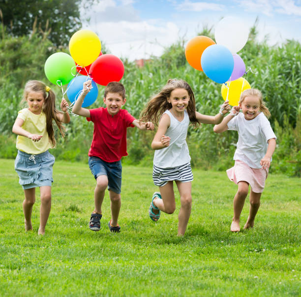 istock Four glad kids running on green lawn 863521658