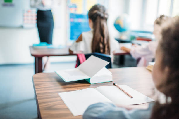 kids sitting at desks in class kids sitting at desks in class and listening to teacher classroom empty education desk stock pictures, royalty-free photos & images