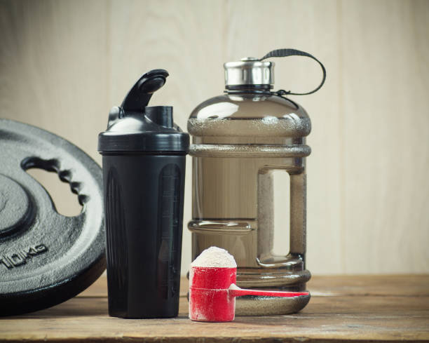 scoop of protein powder necessary nutrition for muscle recovery after an intensive workout, next to a protein shaker stock photo
