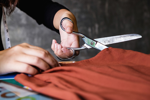Close up of hands, Young woman dressmaker or designer working as fashion designers measure and Cutting for clothes, profession and job occupation, Fashion Designer Stylish Concept.
