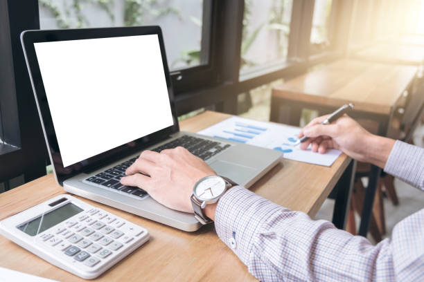 istock Elegant businessman working on his laptop in a coffee shop, analyzing data and graph, using calculator calculate, young man typing on computer sitting at wooden table 863564936