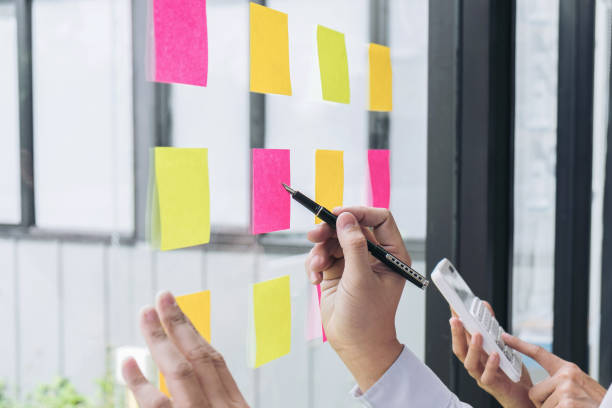 istock Young creative professional leader using notes in glass wall to writing strategy business plan, businesspeople discussing and planning concept 863564970