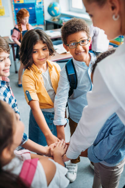 istock teacher and pupils making team sign 863568480