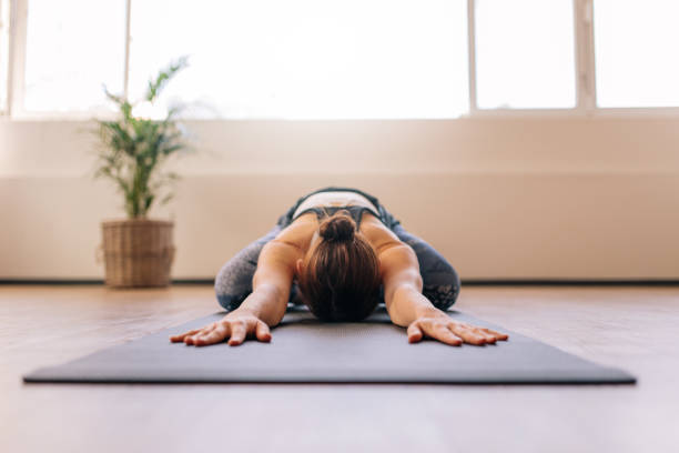 Fitness woman working out on yoga mat Fit woman performing child yoga pose at gym class. Fitness woman working out on yoga mat indoors. yoga studio photos stock pictures, royalty-free photos & images