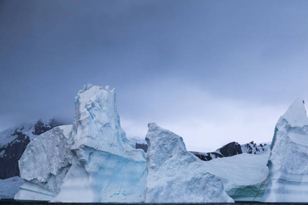 istock Huge iceberg set against dark clouds 863592224