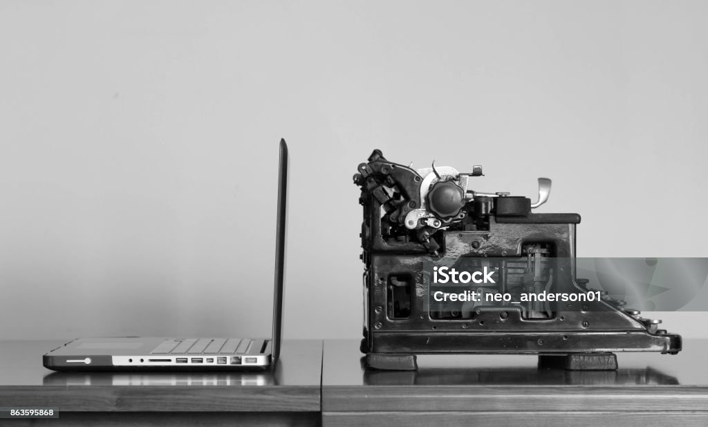 Laptop and typewriter, modern and vintage Modern laptop and old typewriter Computer Monitor Stock Photo