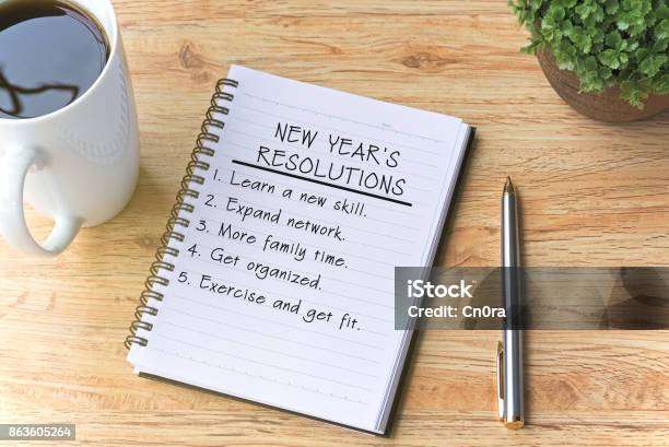 Resoluciones De Año Nuevo Escritas En El Bloc De Notas Con Pluma Café Y Planta En Mesa De Madera Foto de stock y más banco de imágenes de Propósito de año nuevo